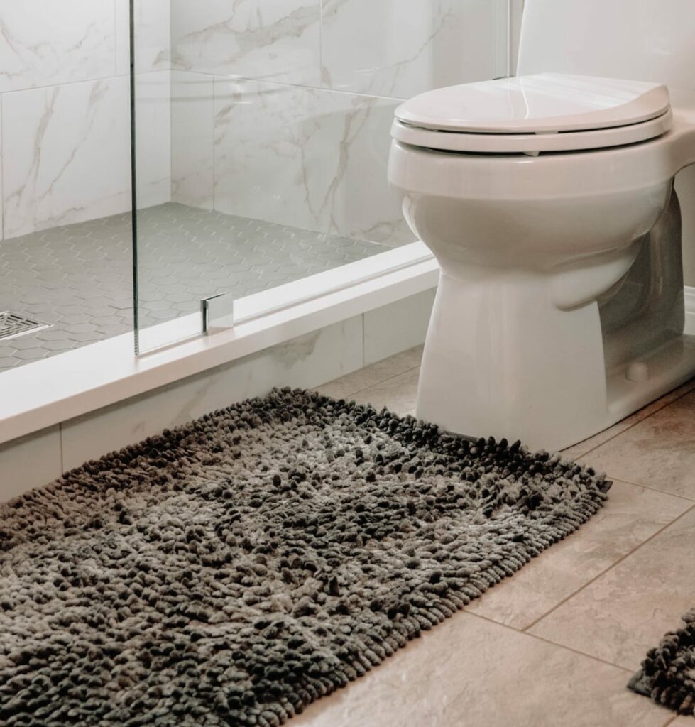 Modern bathroom with tiled walk-in shower and dark gray bath rug