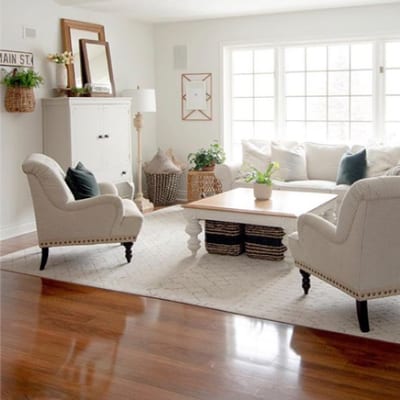 Living room with freshly-polished floors, a wood coffee table with a white base and light-colored furniture