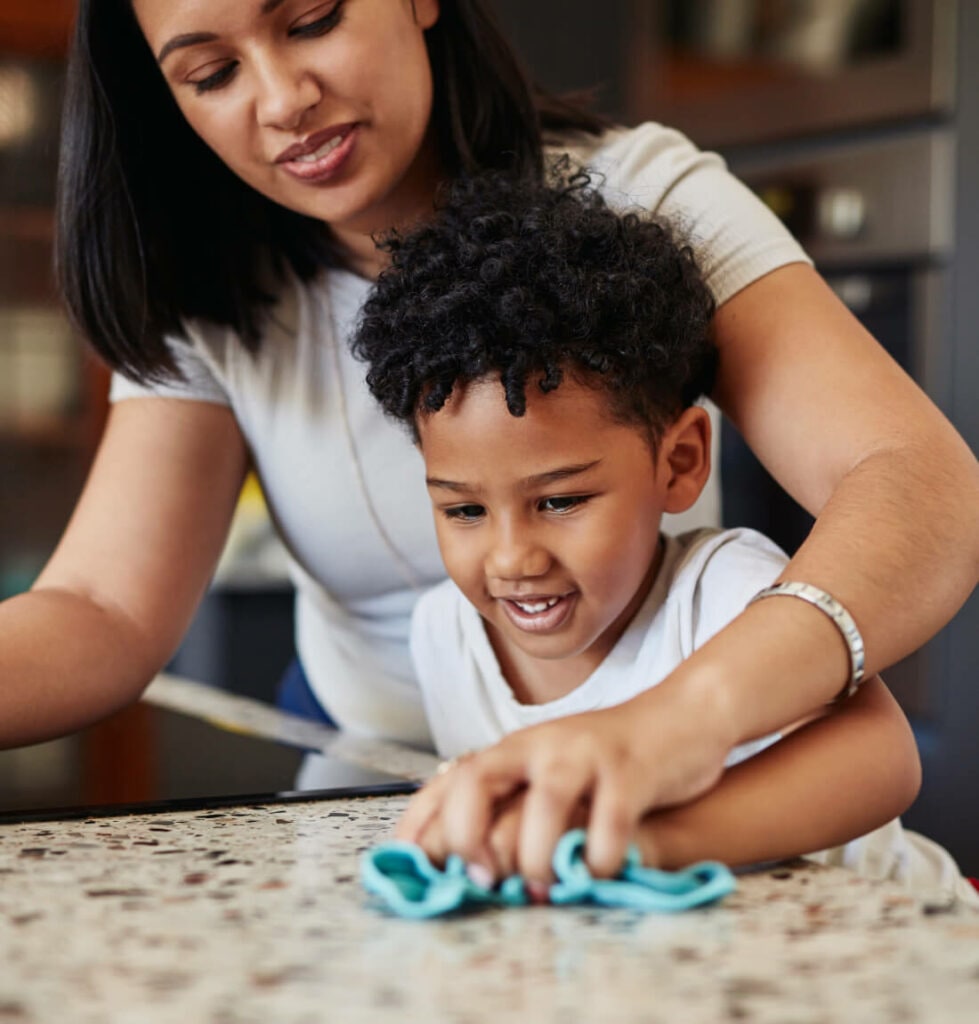 Mother and young son cleaning granite countertop with teal microfiber cloth